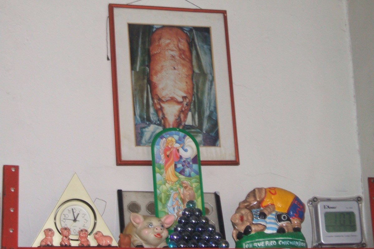 Altar a la lechona, con la foto de una lechona, un reloj, cinco cerditos en porcelana de diferentes tamaños, y otro cerdo de plástico